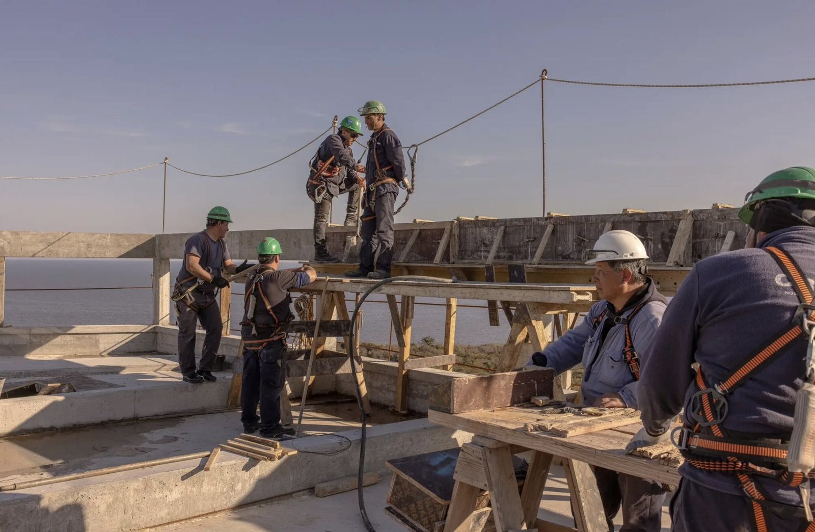 Operários com capacete em obra de concreto à beira do rio, imagem que ilustra o projeto da Praxis de uma cidade para a era pós-IA no Uruguai